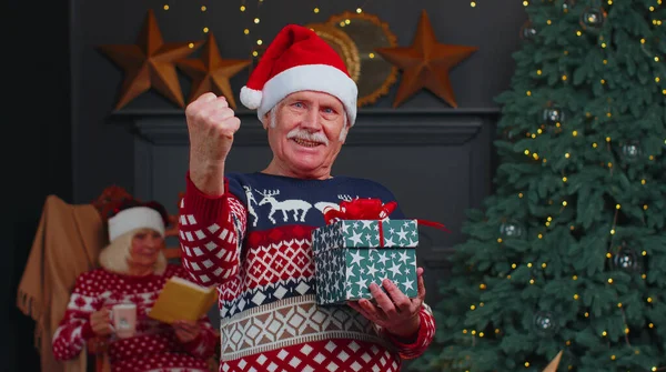 Старший дедушка в рождественском свитере праздновать успех выиграть крик делает жест победителя руки — стоковое фото