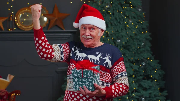 Älterer Opa im Weihnachtspulli feiert Erfolg mit Siegerhändegeste — Stockfoto