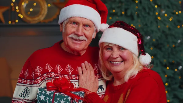 头戴圣诞礼帽的年轻夫妇一家人一边看着相机一边拥抱在家里庆祝圣诞节 — 图库照片