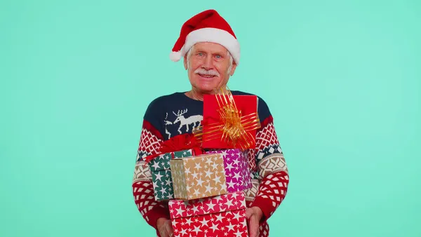 Старший дідусь на різдвяному светрі тримає багато подарунків на Новий рік. — стокове фото