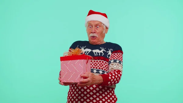 Vovô homem em camisola Santa Natal recebendo caixa de presente, expressando felicidade espanto — Fotografia de Stock