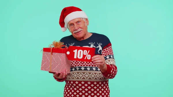 Дедушка в рождественском свитере с подарочной коробкой и 10-процентной скидкой — стоковое фото