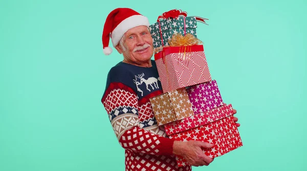 Старший дідусь на різдвяному светрі тримає багато подарунків на Новий рік. — стокове фото