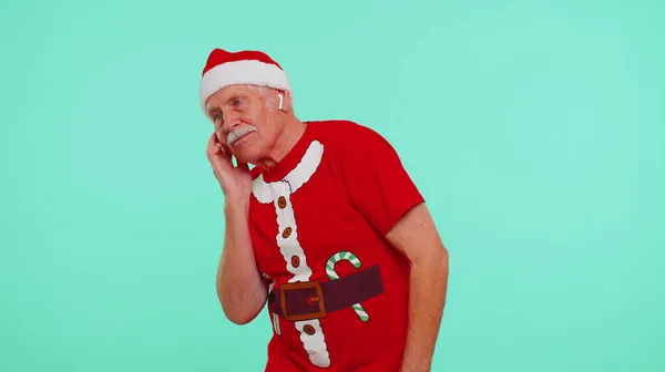 Старший різдвяний дідусь слухає музику за допомогою навушників, танцює весело диско, обдурюючи навколо — стокове фото