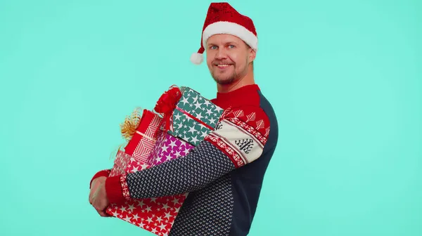 Bonito homem elegante em camisola de Natal segurando muitas caixas de presente Ano Novo apresenta venda de compras — Fotografia de Stock