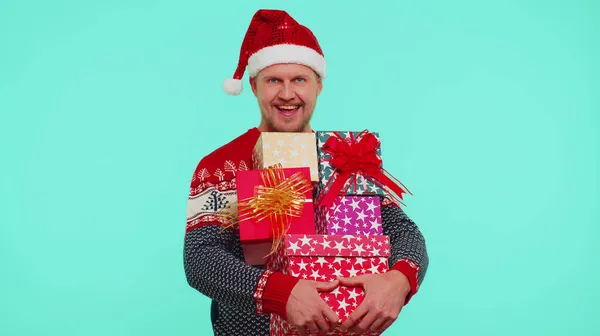 Приємний один стильний чоловік на різдвяному светрі, який тримає багато подарунків Нового року, пропонує покупки. — стокове фото