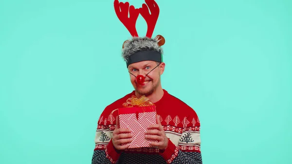 Homem alegre em suéter chapéu de Natal de Santa recebendo caixa de presente, expressando felicidade espanto — Fotografia de Stock