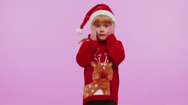 Noel süveteri giyen çocuk aniden kazanılan zaferle şaşkınlıkla el kaldırıyor.