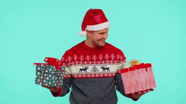 Noel Baba süveter giyen neşeli adam iki Noel hediyesi kutusu sunuyor, ellerini kameraya uzatıyor. — Stok video