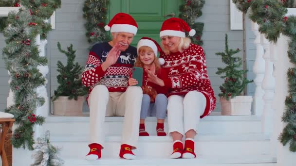 Семья бабушки и дедушки с внучкой делают селфи на мобильном телефоне, видео-звонок онлайн, Рождество — стоковое видео