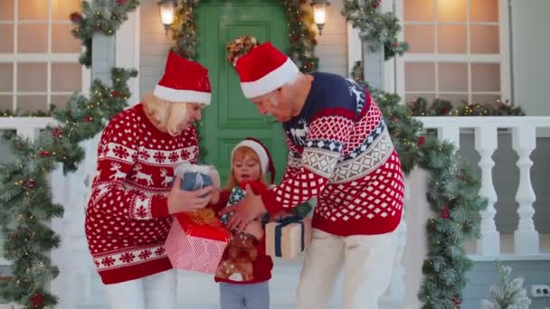 Mature grandparents family with granddaughter exhcanging gifts boxes presents for Christmas at home — Stock Video