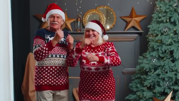 Пожилая семейная пара бабушка танцует в украшенной домашней комнате с елкой — стоковое видео