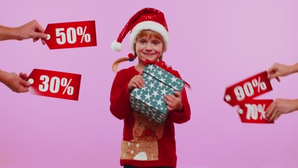 Küçük kız elinde hediye kutuları tutuyor ve Noel indirimleri alıyor. Yazılar, afişler. — Stok video