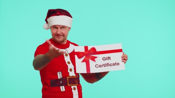 Hombre en camiseta roja Santa sombrero de Navidad presentando tarjeta de regalo vale de cupón de regalo para el ganador — Vídeo de stock