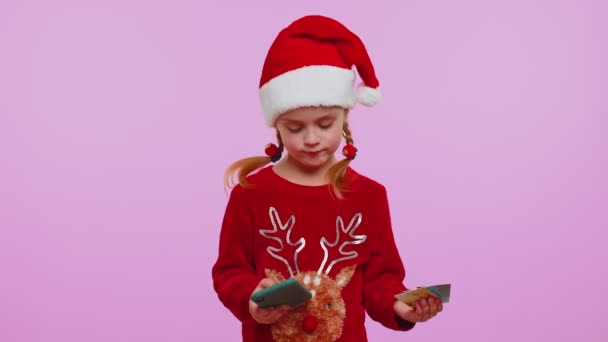 Dívka ve vánočním svetru pomocí kreditní karty smartphone při převodu peněz nakupování on-line