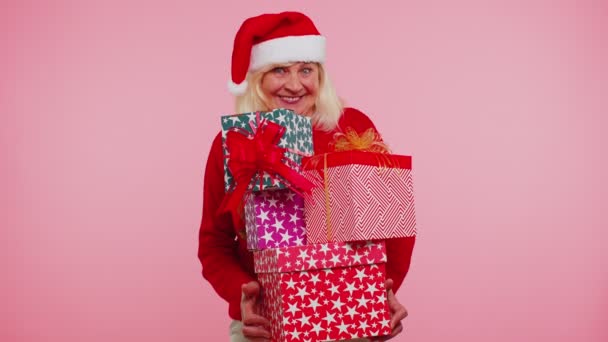 Бабуся на різдвяному светрі Санті, яка тримає багато подарунків на Новий рік, дарує покупки. — стокове відео