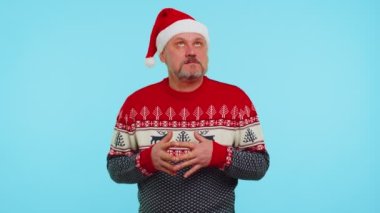Noel Baba şapkalı neşeli adam hediye kutusunu alıyor, mutluluğunu ifade ediyor.