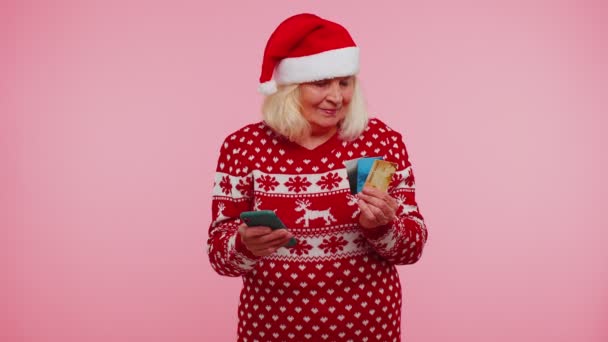 Abuela de Navidad con tarjeta bancaria de crédito, teléfono inteligente durante la transferencia de dinero de compras en línea — Vídeo de stock