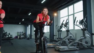 İki arkadaş grubu. Modern spor salonunda spor yapan, antrenman yapan, bisiklete binen iki kadın.