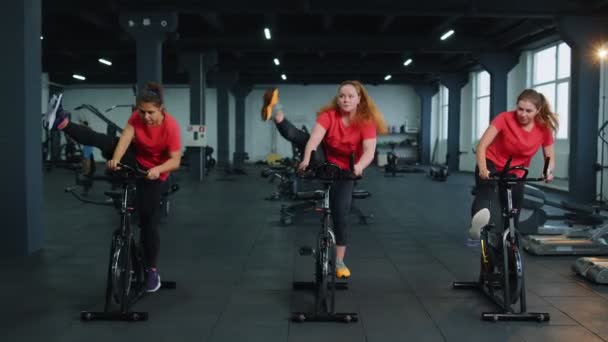 Skupina usměvavých přátel ženské třídy cvičení, trénink, točení na stacionárním kole v moderní tělocvičně — Stock video