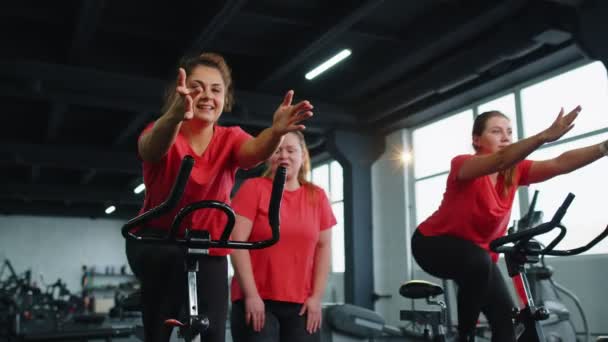 Sağlıklı bir beyaz kadın grubu spor salonunda sabit bisiklet üzerinde egzersiz yapıyor. — Stok video