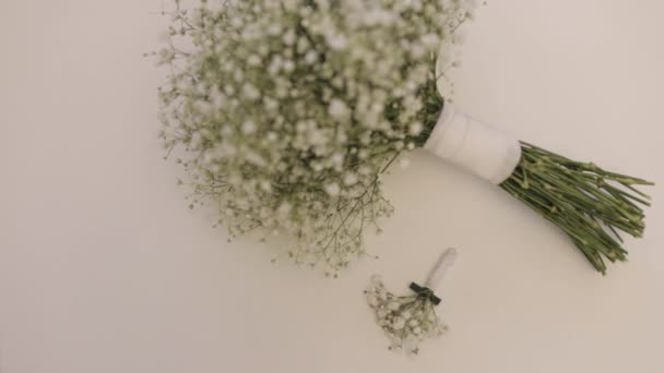 Dwa ślubne bukiety panny młodej i druhen białych cygańskich kwiatów leżą na białym tle — Wideo stockowe