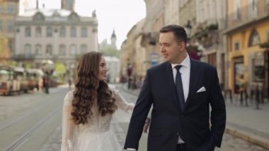 Yeni evlilerin portresi, beyaz gelinin yürüyüşü, kucaklaşması, şehir caddesinde sarılması, düğün çifti.