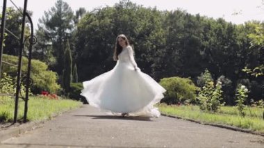 Parkta damadı bekleyen gelinlik ve duvak içinde güzel ve güzel bir gelin. Yavaş çekim