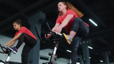 Grup atletik kızlar spor salonunda bisiklet sürme egzersizleri yapıyorlar.