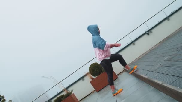Esporte mulher no sportswear usa capuz fazendo treino, passo cardio exercitando treinamento no telhado da casa — Vídeo de Stock