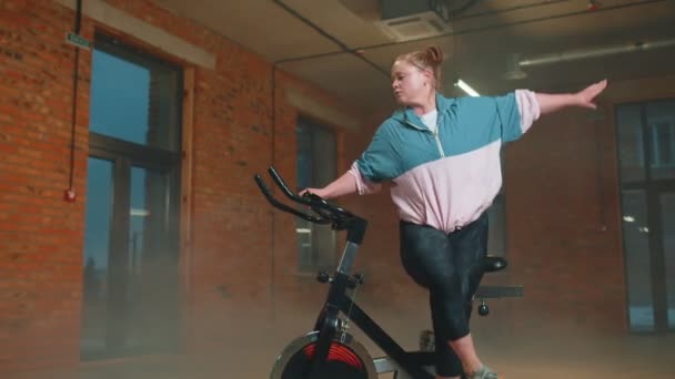 Здорова кавказька жінка займається фізичними вправами на стаціонарному велосипедному велосипеді в спортзалі "Повільний рух" — стокове відео