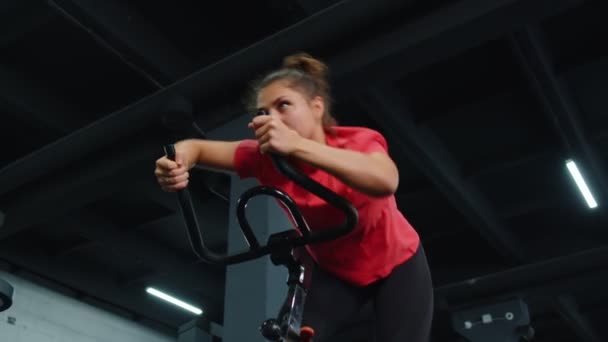 Mujer realiza entrenamiento de resistencia aeróbica rutina de entrenamiento cardiovascular en los simuladores, entrenamiento de ciclo — Vídeo de stock