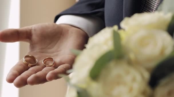 Novio en chaqueta gris sosteniendo anillos de boda en la palma de su mano, el hombre apretó los anillos en su puño — Vídeos de Stock
