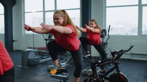 Group of smiling friends women class exercising, training, spinning on stationary bike at modern gym — Stockvideo