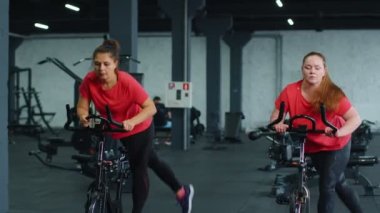 Spor salonunda bisiklet çevirme antrenmanına katılan atletik kadın grubu, içeride kilo kaybı.