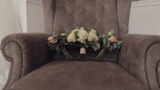Três noivas de casamento e buquês de damas de honra de flores de rosas brancas e rosa deitam-se na cadeira cinza — Vídeo de Stock