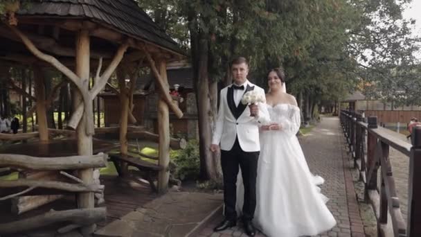 Jolies jeunes mariés mariés mariés caucasiens avec bouquet dans le parc, mariage couple première réunion — Video