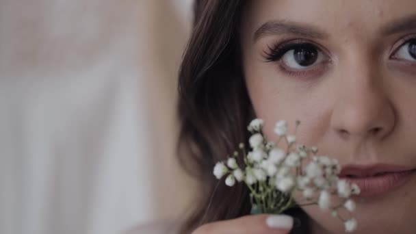 Primer plano de hermosa cara encantadora de novia chica mirando a la cámara y sonriendo con flores ramo — Vídeo de stock