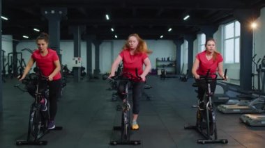 Bir grup kız, bisiklet simülatörlerinde aerobik antrenmanı yapıyor.
