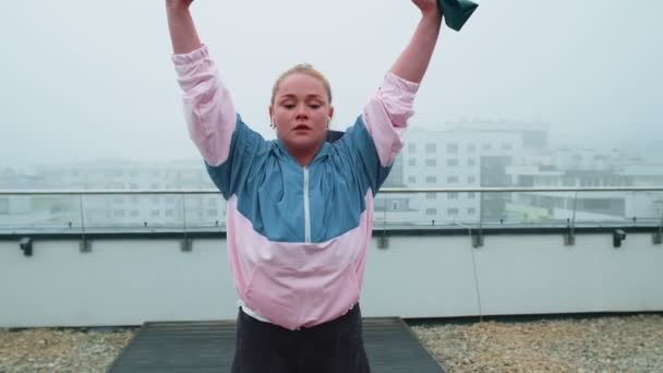 Menina desportiva em sportswear faz ioga alongamento exercício usando elástico no telhado da casa ao ar livre — Vídeo de Stock