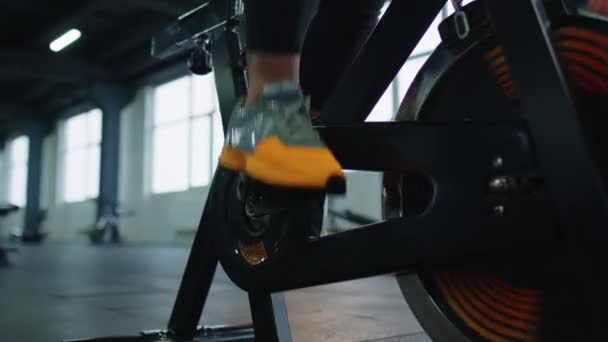 Zbliżenie atletyczna kobieta nogi spinning ćwiczenia na stacjonarnym rowerze rowerowym, w pomieszczeniach — Wideo stockowe