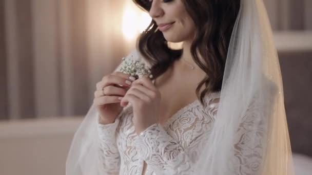 Gros plan de belle jeune mariée élégante souriante regardant bouquet de fleurs gypsophila à la maison — Video