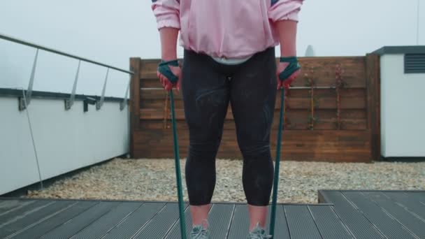 Sporty girl in sportswear does yoga stretching exercising using rubber band on roof of house outdoor — Stock Video