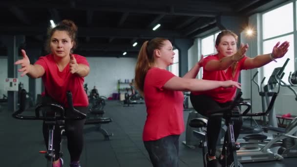 Gruppo di ragazze esegue allenamento aerobico allenamento cardio routine su simulatori di bici, ciclo di allenamento — Video Stock