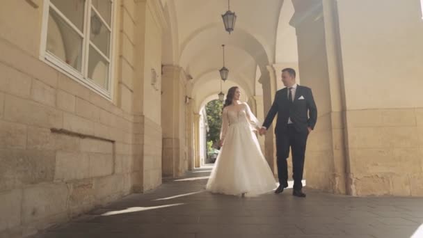 Nygifta porträtt, kaukasiska brudgummen brud promenader, hålla händerna på Lviv city street, bröllop par — Stockvideo