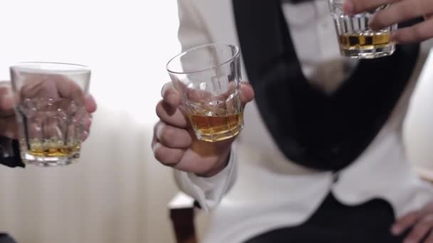 Λόχος γαμπροί φίλοι κρατώντας και σφίγγοντας ποτήρια αλκοολούχων ποτών ουίσκι στα χέρια τους — Αρχείο Βίντεο