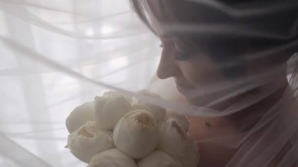 Menyasszony fehér ruhában tartózkodik ablak közelében virágokkal csokor, esküvői reggeli előkészületek otthon — Stock videók