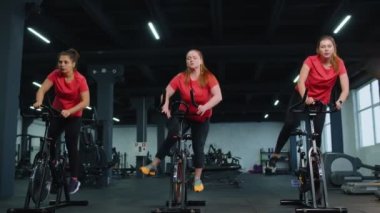 Grup atletik kızlar spor salonunda bisiklet sürme egzersizleri yapıyorlar.