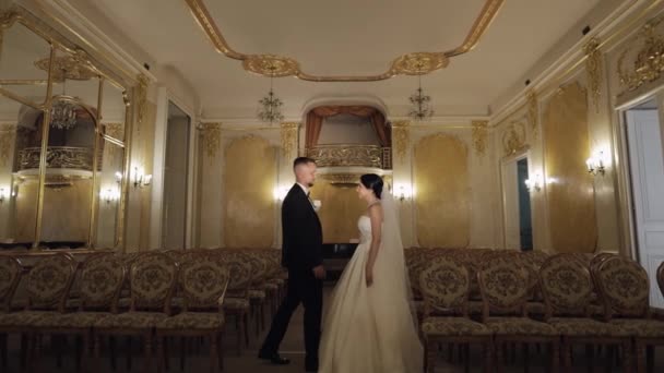 Newlyweds portrait, caucasian groom bride walking, embracing, hugs in large room, wedding couple — 图库视频影像
