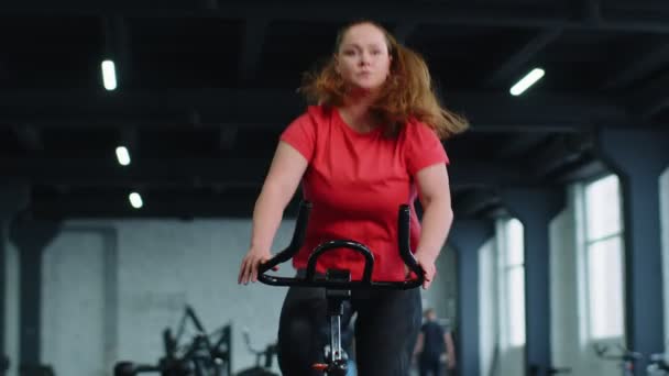 Sportowa kobieta jeżdżąca na rowerze wirującym stacjonarny trening rutynowy w siłowni, utrata wagi w pomieszczeniach — Wideo stockowe